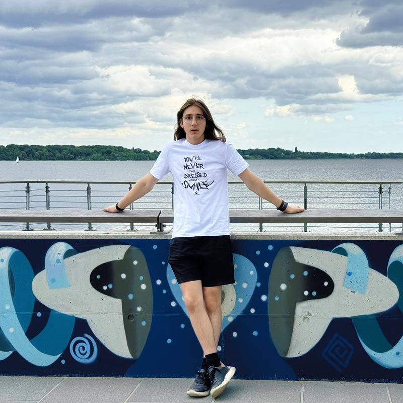 Junger Mann steht an einer Grafittiwand am Meer.